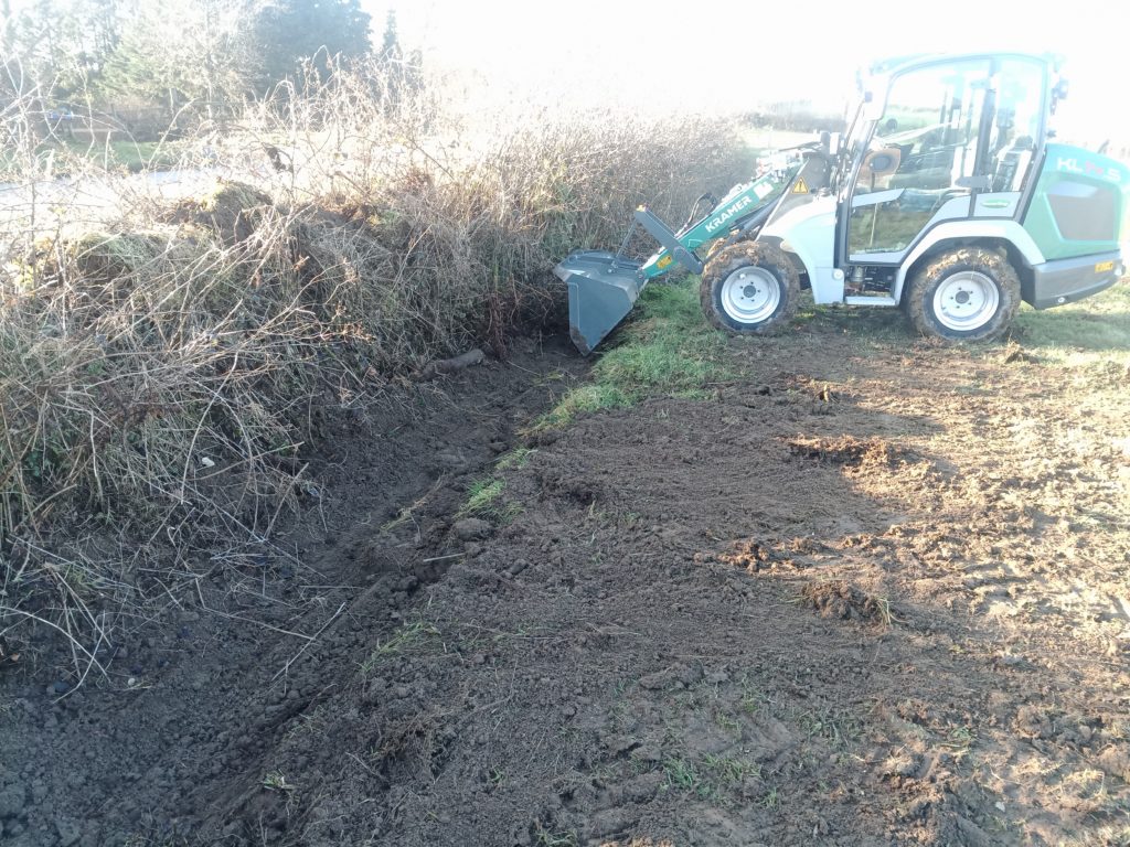 Kramer KL14.5 clearing clogged drainage ditches to improve drainage from the meadow